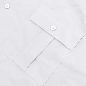 Detailed close-up showing the breast pocket with a buttoned flap on a white linen shirt fabric