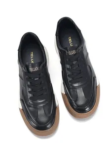 Vista dall'alto di sneakers casual da uomo in pelle nera con suole spesse in gomma marrone