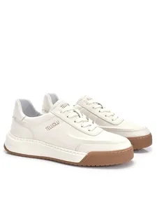Dettaglio laterale di sneaker in pelle bianca da uomo con suola spessa marrone