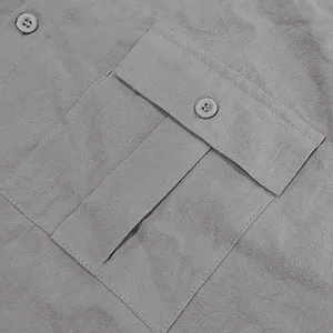 Macro detail showing the flap pocket and button texture on a men's gray linen casual shirt