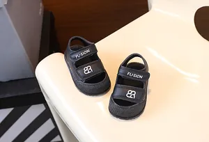 Nahaufnahme schwarzer Baby-Sandalen mit Klettverschluss und FU-SION Markenlogo