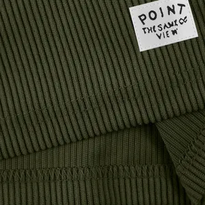 Macro view of the olive green corduroy fabric and white patch detail on men's shorts