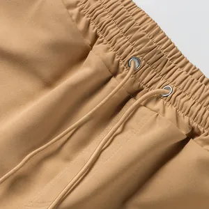 Detailed close-up of elastic waistband and drawstring on tan cargo shorts