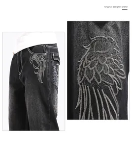 Detailed close-up of grey wing embroidery on men's baggy black hip hop denim jeans.