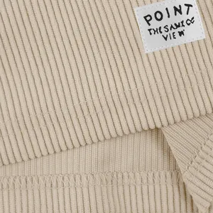 Detailed macro view of beige corduroy shorts fabric and white woven brand label tag