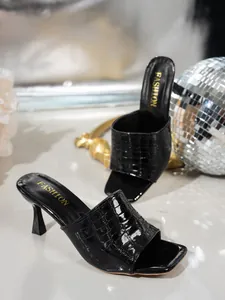 Detail of black crocodile embossed kitten heel mules with elegant square toe design.