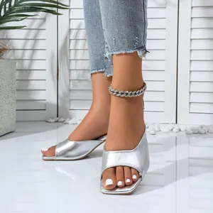 Detail of silver metallic open-toe mules and chunky rhinestone chain anklet