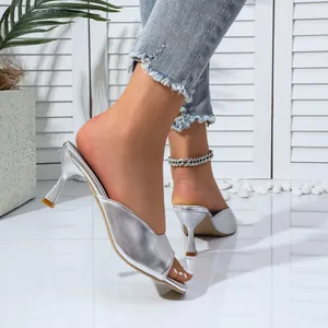 A macro view of elegant silver metallic kitten heel mules worn with stylish denim