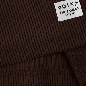 Macro detail of dark brown ribbed fabric texture showing the woven brand label on shorts
