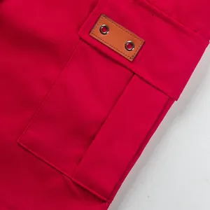 Detail of cargo pocket on red high street shorts with leather patch and metal eyelets