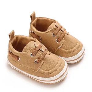Close-up view of brown canvas infant walking shoes featuring a soft white rubber sole