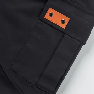 Macro detail view of men's cargo shorts pocket featuring leather patch and metal eyelets.