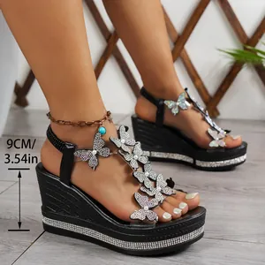 Detail of black wedge sandals with sparkly butterflies and 9cm platform heel.