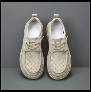 Top-down view of men's beige perforated leather casual shoes with laces on gray background