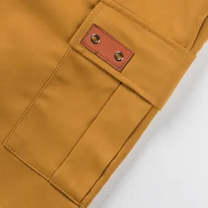 Close-up of cargo pocket detail with leather patch on mustard yellow shorts