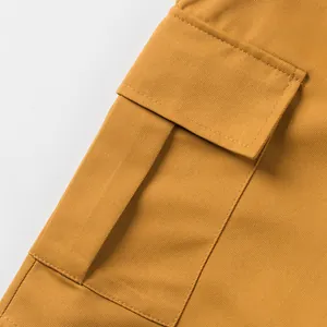 Close-up of the durable twill fabric and large cargo pocket on mustard yellow shorts