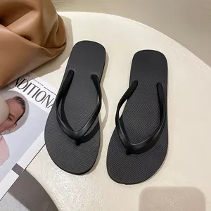 Classic black non-slip rubber flip-flops for women in a minimalist summer beach setting