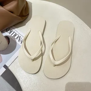 Detailed view of minimalist beige flip-flops on a textured neutral surface