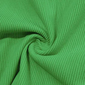 Detailed macro view of soft green corduroy fabric with a distinct ribbed texture and swirls