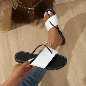 Detailansicht schicker flacher Damen-Sandalen mit modernem schwarz-weißem Farbblock-Design.
