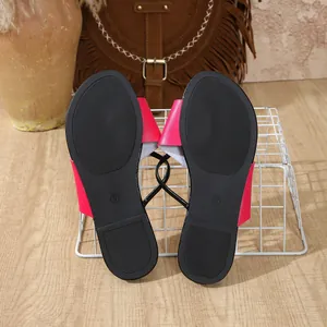 Detaillierte Ansicht der schwarzen rutschfesten Sohle rosa flacher Damen-Sandalen.