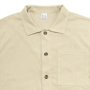 Close-up detail of beige corduroy men's shirt showing collar, buttons and chest pocket