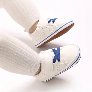 Side view of white baby walking shoes with blue laces and soft non-slip soles.