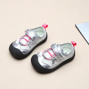 Draufsicht auf silber-rosa Kinder-Sandalen mit Zehenschutz auf beigem Hintergrund.