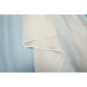 Macro detail shot of soft white chiffon fabric showing high-quality seam work and texture.