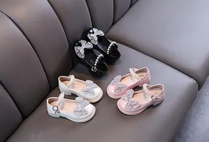 Close-up detail of girls princess shoes featuring rhinestone butterflies and pearl straps