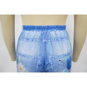 Detailed close-up of elastic waistband and floral butterfly print on denim-look casual pants
