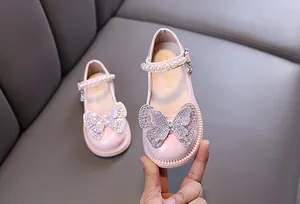 Detailed close-up view of pink princess shoes with rhinestone butterfly and pearl strap