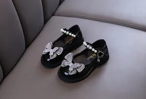 Detailed view of girls' black patent leather princess shoes with rhinestone butterfly