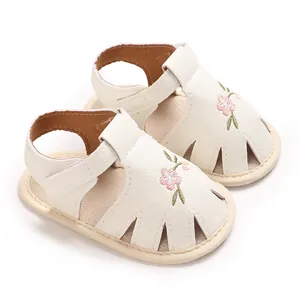 Primer plano del bordado floral en sandalias para bebé color crema de suela blanda