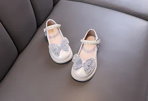 Detail view of white girls princess shoes with large rhinestone butterfly and pearls