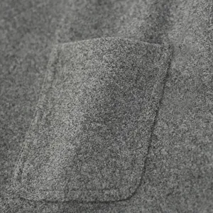 Primer plano del bolsillo de un chaleco de lana gris con textura y costuras.