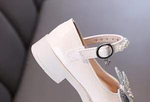 Close-up of girl's patent leather princess shoe with pearl strap and rhinestone detail