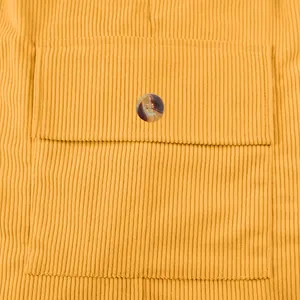 Detailed close-up view of mustard yellow corduroy shorts with a buttoned pocket design