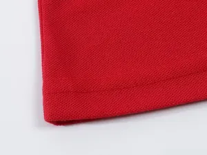 Macro view of bright red pique knit Polo shirt fabric showing double-stitched hem detail