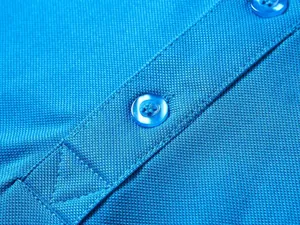 Dettaglio macro del tessuto in cotone piqué blu traspirante e dei bottoni su una polo da uomo