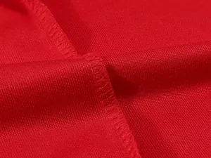 Detailed macro view of the breathable red polo shirt fabric and its durable stitching