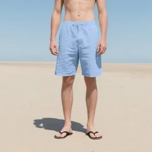 Detail of men's casual light blue linen shorts on a beach background with drawstring.