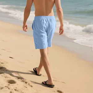 Man wearing light blue loose linen summer shorts walking on a sunny sandy beach coast