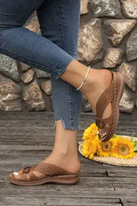Detailed side view of brown wedge sandals with floral accents and laser-cut patterns