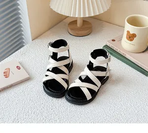 Sandalias romanas blancas para niñas con correas cruzadas y cierre de hebilla.