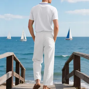 Mann in weißem Poloshirt und Leinenhose an einem Pier am Meer mit Segelbooten