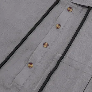 Close-up of grey linen henley shirt showing fabric texture and black piping details