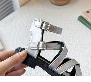 Primer plano de sandalias romanas plateadas para niña con hebillas y acabado metálico.