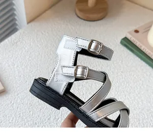 Primer plano de sandalias romanas plateadas para niña con hebillas y tiras de velcro
