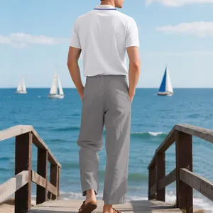 Rückansicht eines Mannes in weißem Polo und grauer Leinenhose an einem Meeressteg.